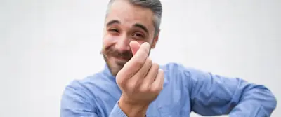 Hombre sonriente hace con los dedos el gesto de plata