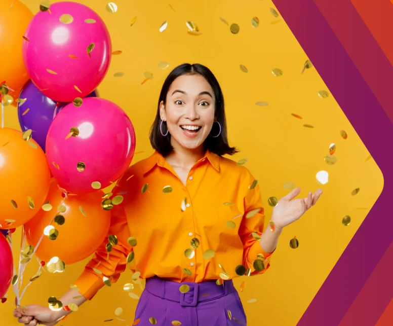 Mujer muy feliz con globos en la mano y papelitos metálicos de fondo. 