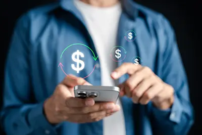 Hombre hace una transferencia desde el celular con íconos de dinero alrededor