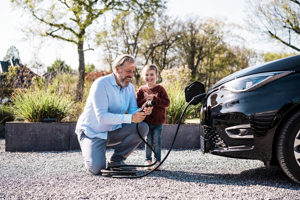 Vater und Tochter laden ein E-Auto mit Ladestecker zuhause