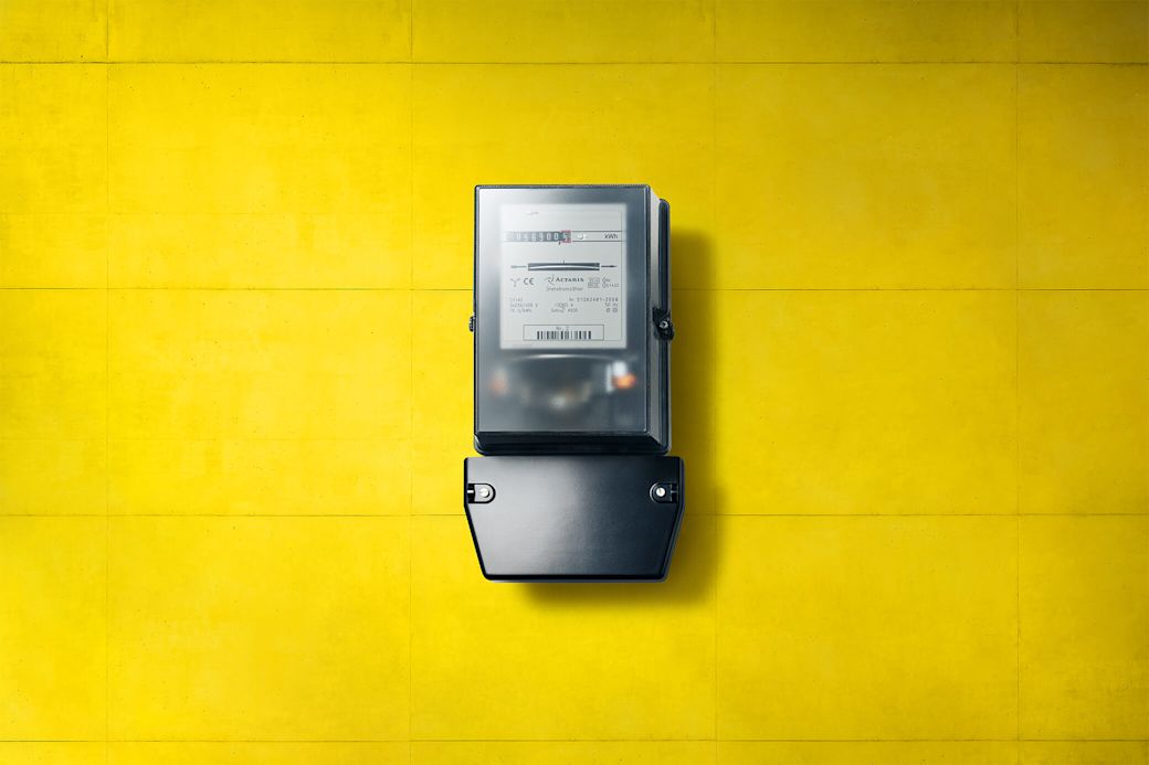 Analoger schwarzer Stromzähler, Ferraris-Zähler, an gelber Wand
