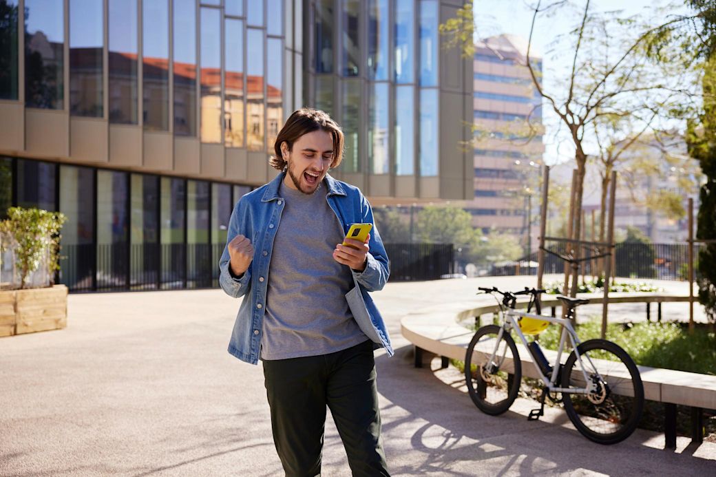 Mann in der Stadt mit gelbem Handy freut sich