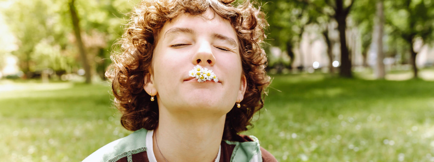 Junge Frau mit Gänseblümchen im Mund entspannt sich im Park