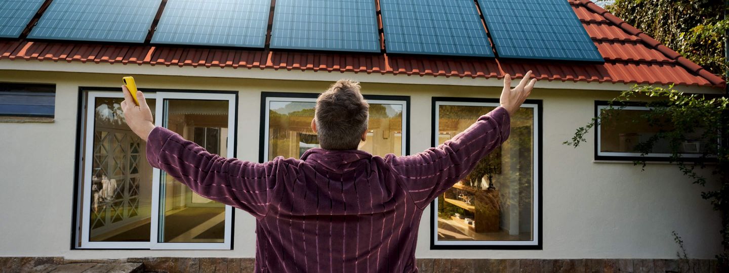 Mann steht vor seiner neuen Solaranlage auf dem Dach