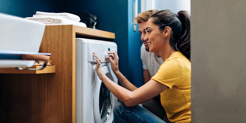 Junges Paar befüllt zusammen eine Waschmaschine.