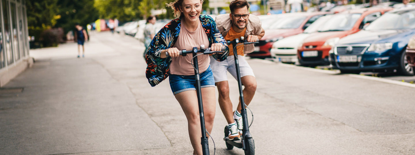 Junges Paar hat Spaß und fährt mit E-Scooter durch die Stadt