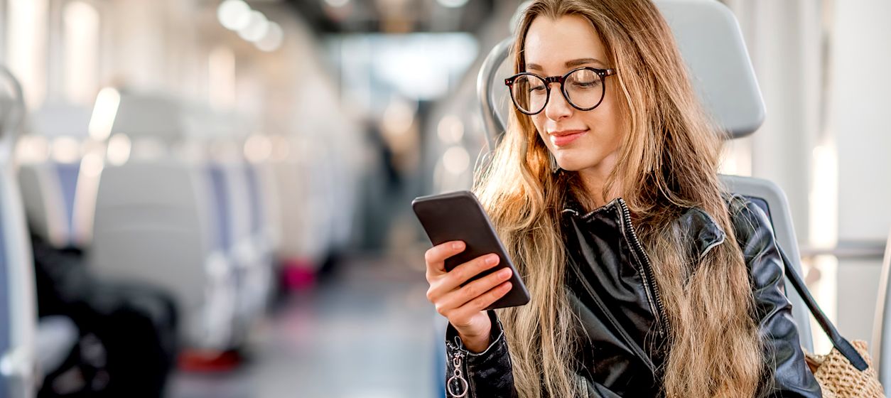 Frau im ÖPV schaut auf Smartphone