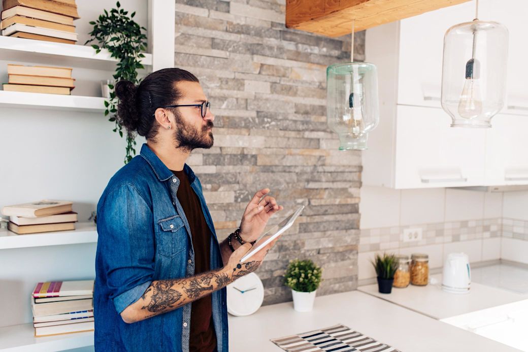 Junger Mann steuert Smart Beleuchtung von Tablet aus in seiner Wohnung