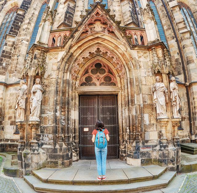 Frau mit Rucksack steht am Eingang der Leipziger Thomaskirche.
