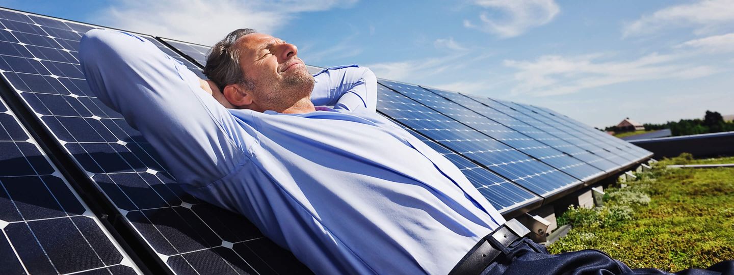 Mann liegt auf einer PV-Anlage und sonnt sich