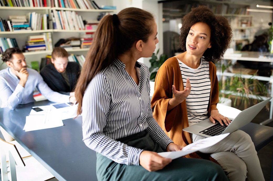 Zwei Frauen unterhalten sich in der Bibliothek