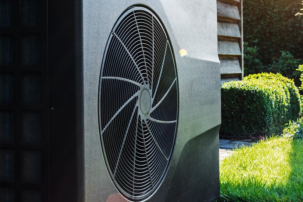 Schwarze Wärmepumpe hinterm Haus im Garten