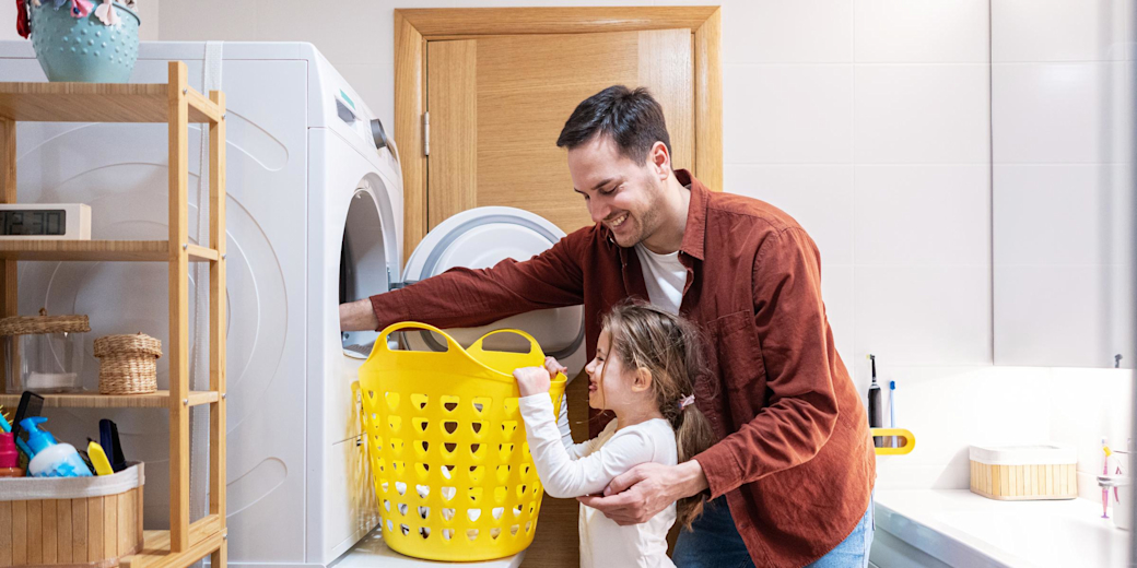 Vater und Tochter holen die Wäsche aus dem Trockner