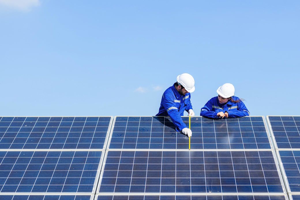 Zwei Techniker überprüfen Solaranlage auf einem Dach