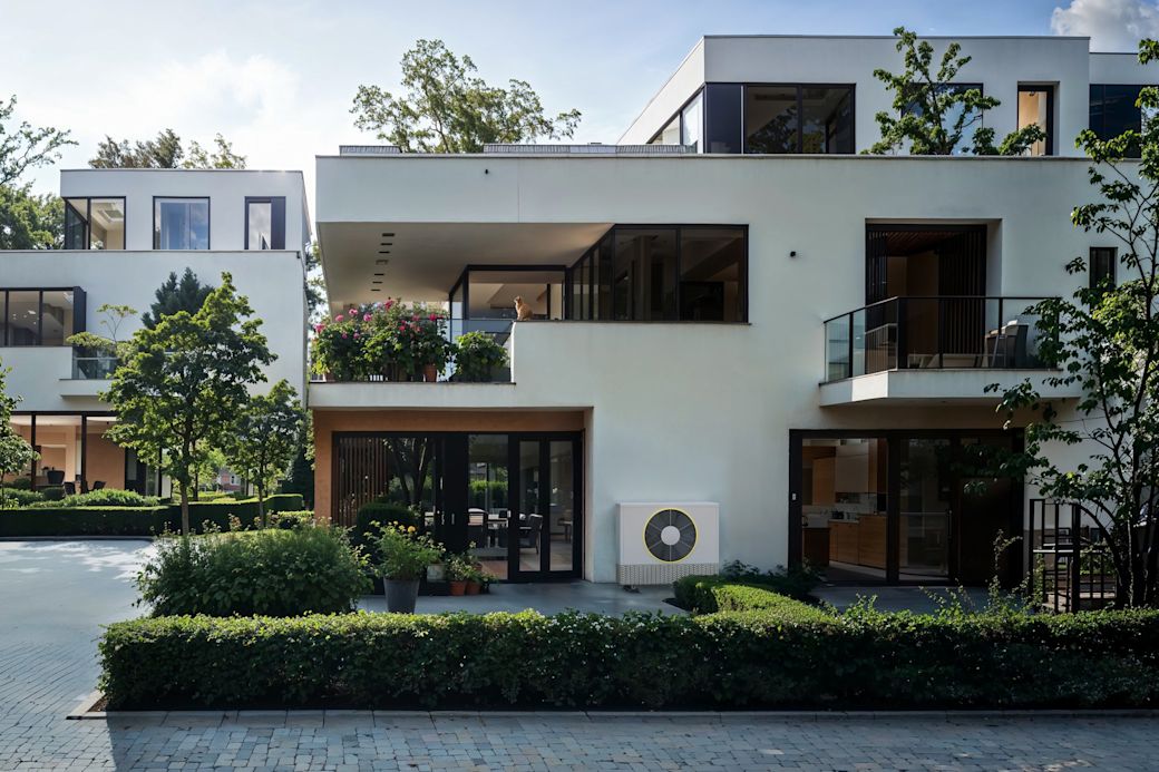 Eine Wärmepumpe vor einem modernen Haus in der Wohnsiedlung