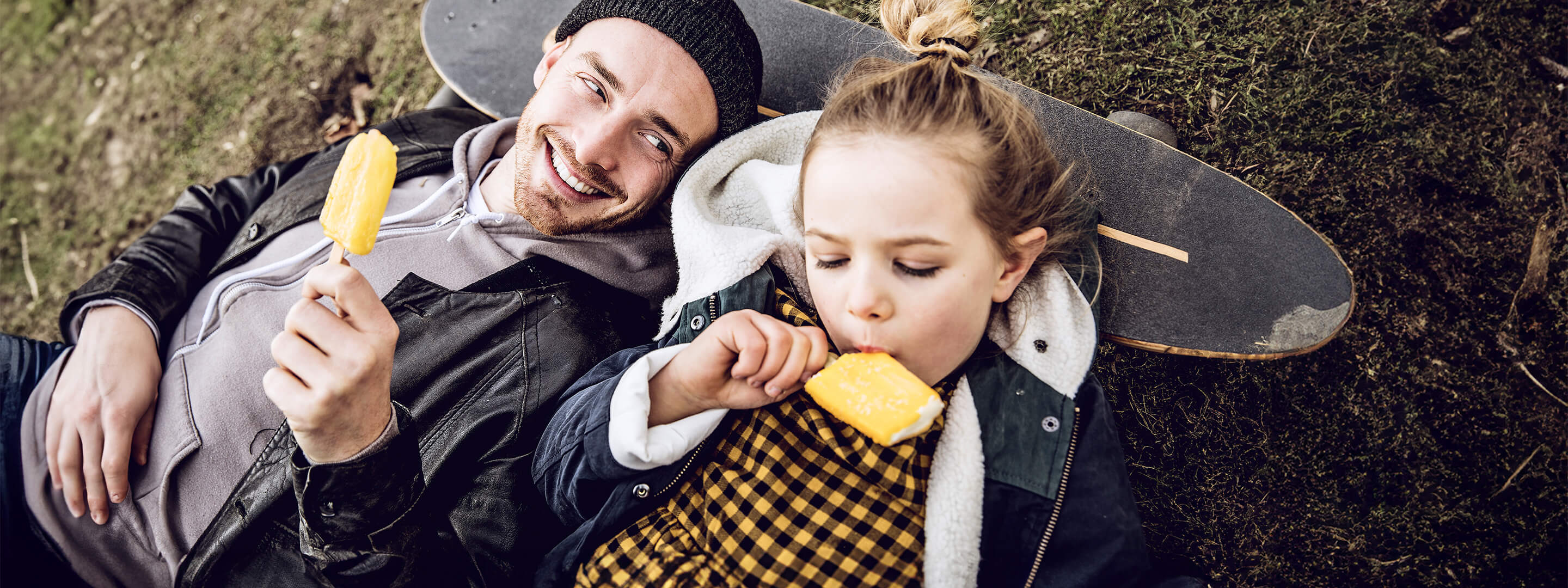Mann und Tochter essen Eis auf dem Skateboard