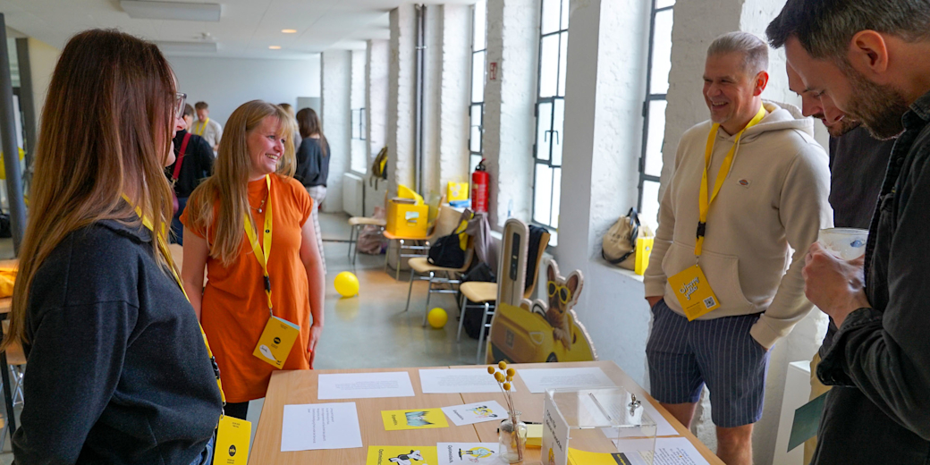 Mitarbeiter steht vor einer Gruppe anderer Mitarbeiter:innen und moderiert eine Schulung.