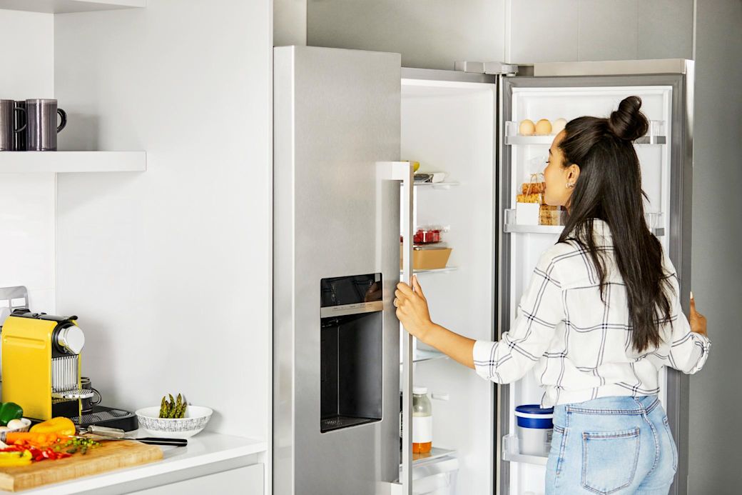 Junge Frau öffnet energieeffizienten Kühlschrank