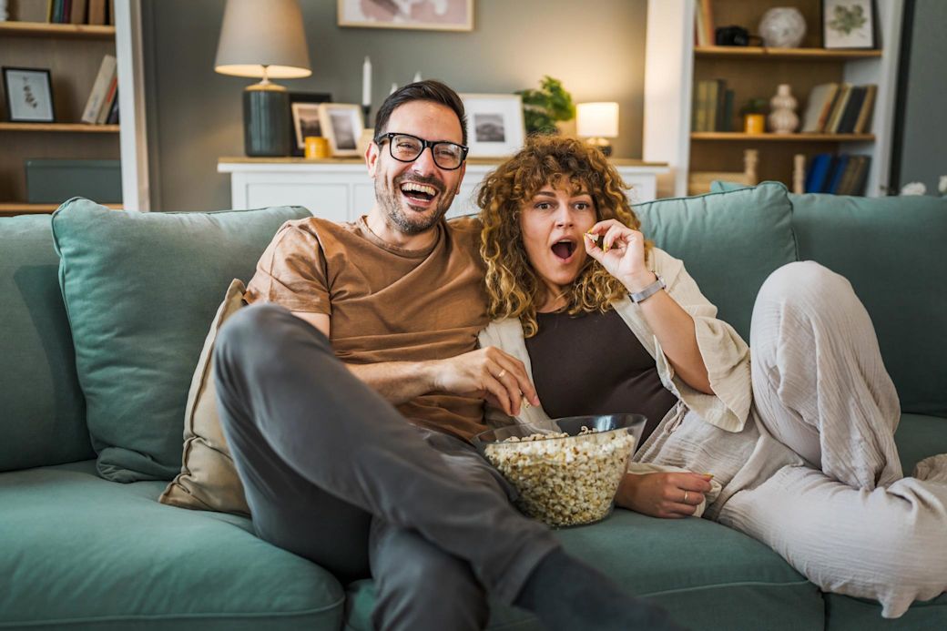 Junges Paar beim Fernsehen auf dem Sofa mit Popcorn