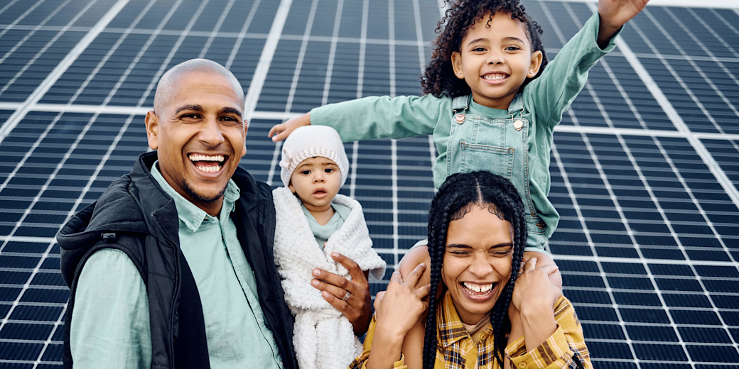 Familie macht zusammen ein Foto vor Solaranlage.