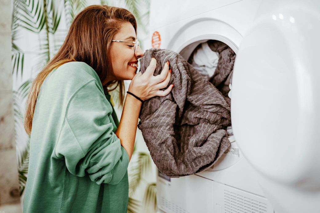 Eine junge Frau nimmt Wäsche aus der Waschmaschine