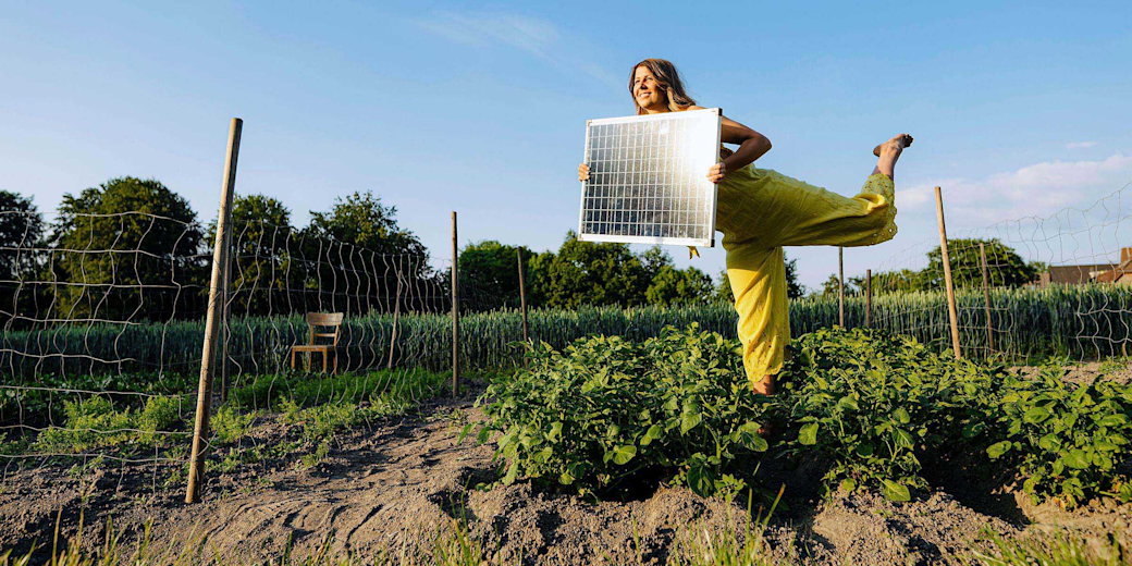 Frau mit Solarmodul in den Händen im Garten.