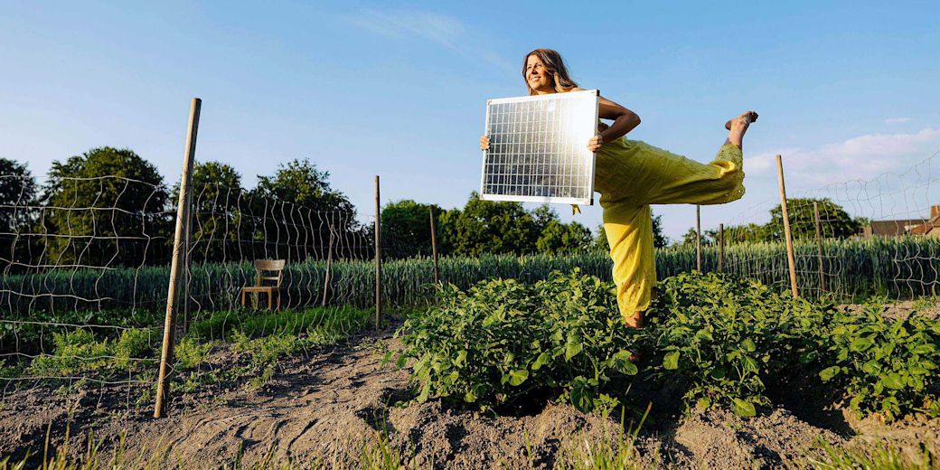 Frau mit Solarmodul in den Händen im Garten.