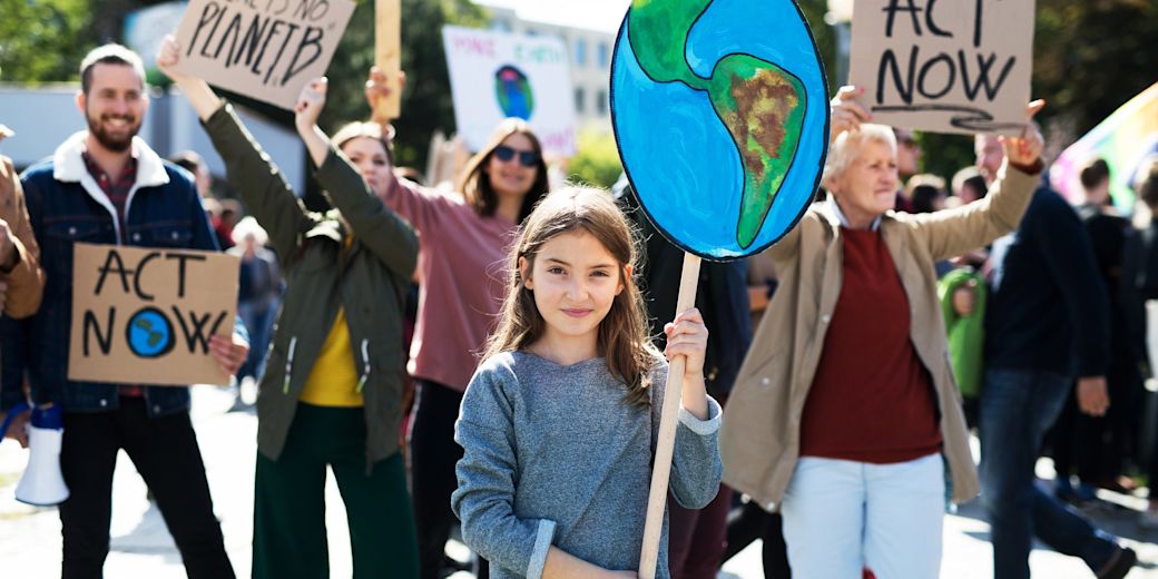 Mädchen hält Abbildung der Erde auf einer Klima-Demo in die Luft