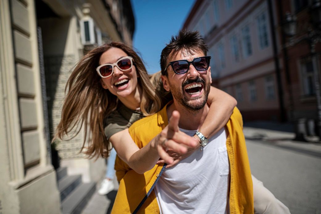 Paar entdeckt Düsseldorf mit Freude. Ein Mann trägt eine Frau huckepack. Spaß in der Innenstadt.