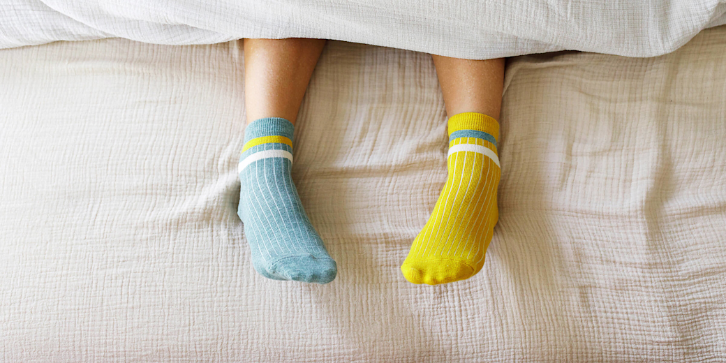 Füße in warmen Stricksocken liegen auf einer Bettdecke