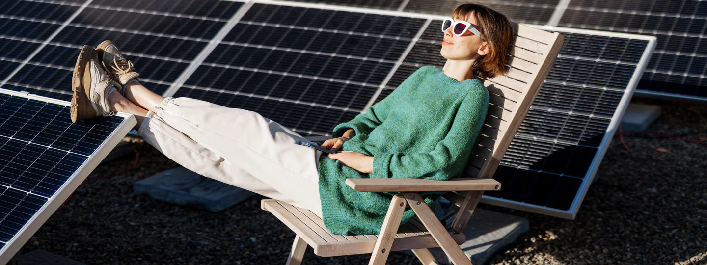 Frau mit Sonnenbrille entspannt auf Dach mit Solaranlage