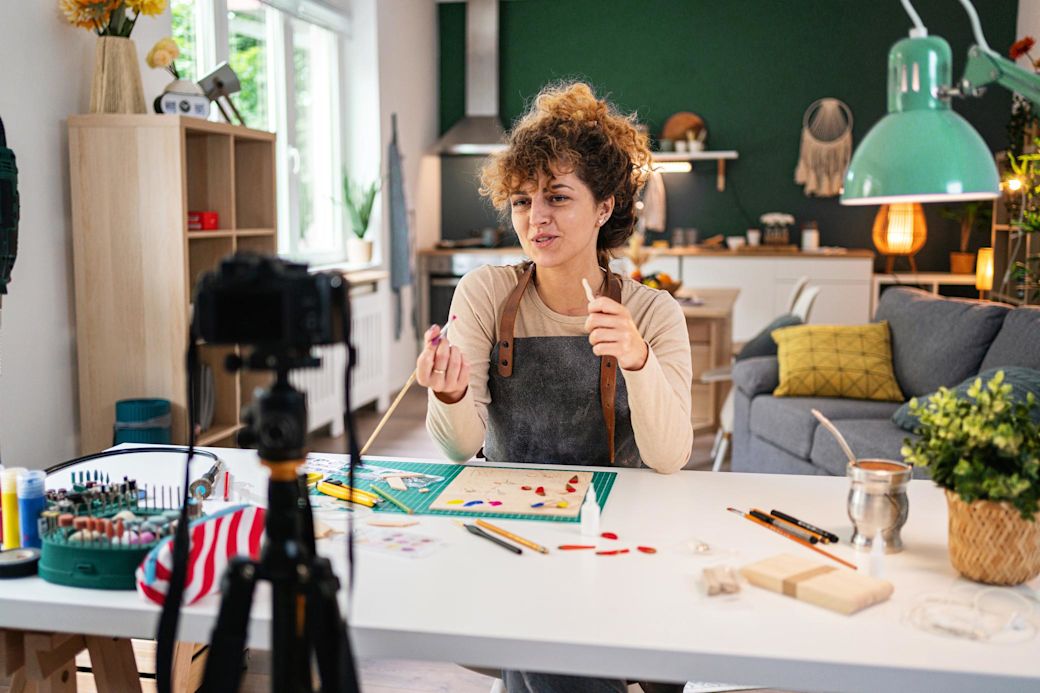 Eine junge Frau bemalt Holz als Do It Yourself Anleitung vor einer Video Kamera