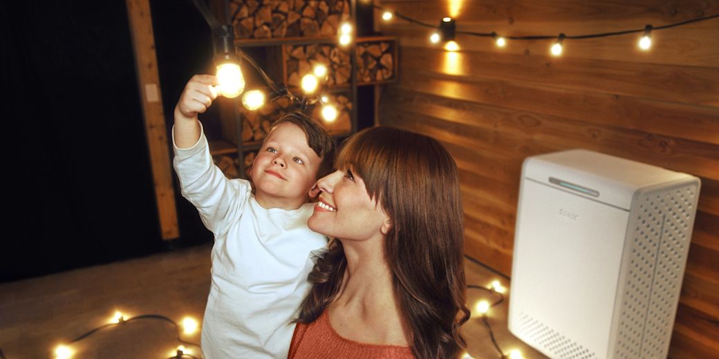 Eine Mutter hält ihren kleinen Sohn auf dem Arm vor einem Heimspeicher