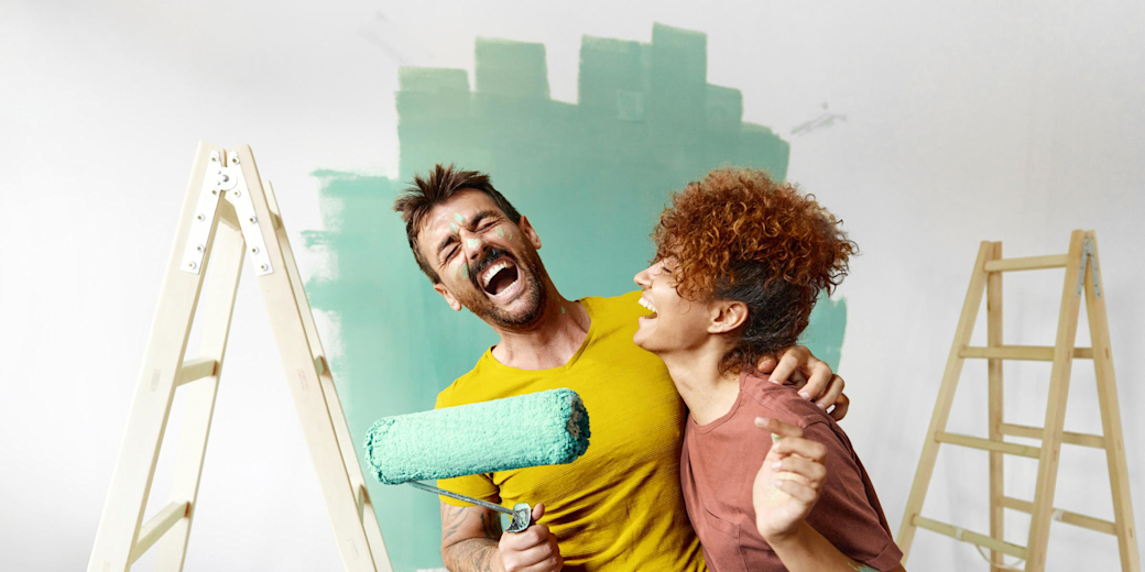 Junges, lachendes Paar streicht die Wohnung grün