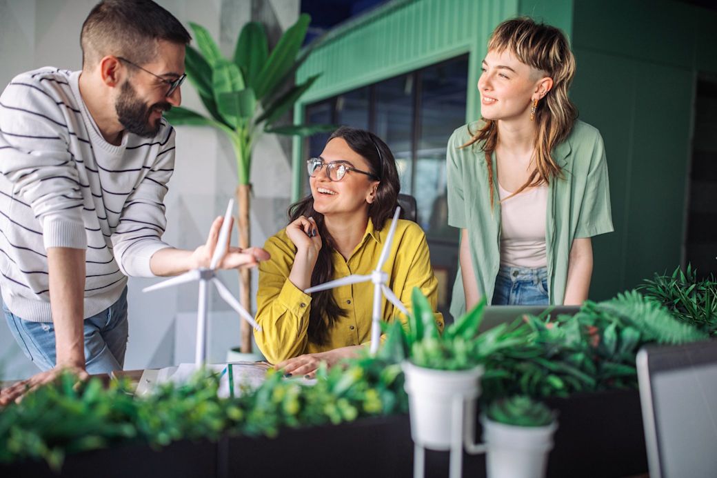 Ein Team aus drei jungen Personen spricht über Stromnetz und Windkraftanlagen im Büro