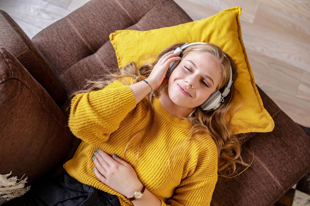 Junge Frau entspannt auf Sofa und hört Musik