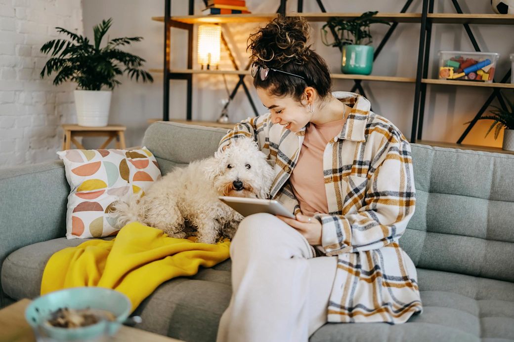 Frau kuschelt mit Hund auf dem Sofa