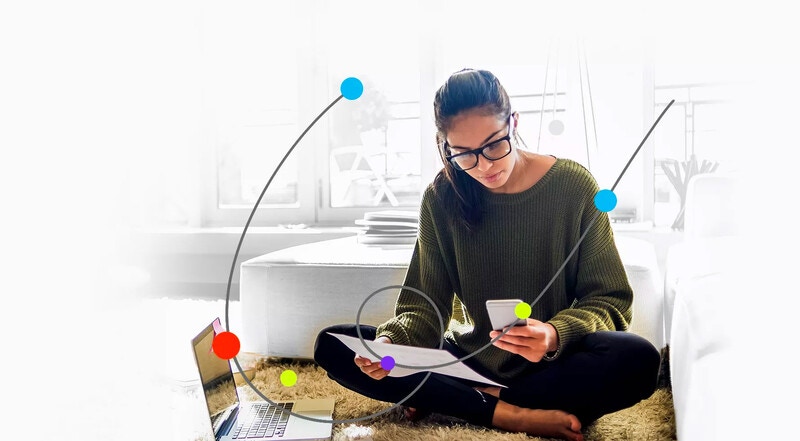 woman holding printed document while looking at phone