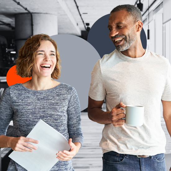 Two smiling coworkers in casual attire, woman holding laptop, man with coffee mug, in modern office with geometric shapes.