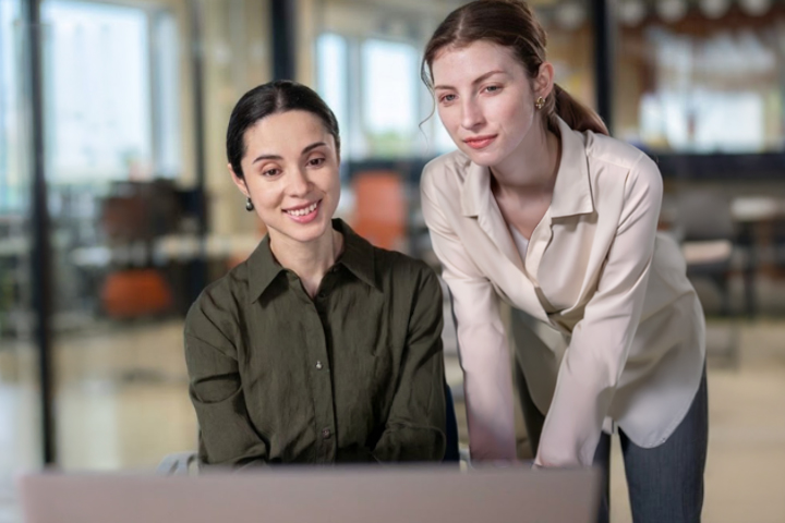 Two women working in an office, collaborating at a computer