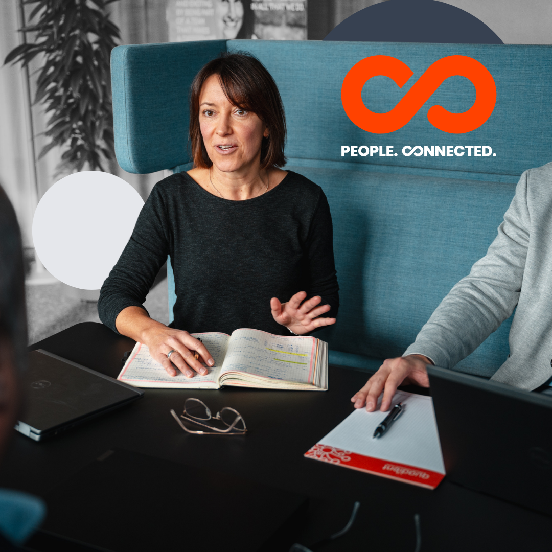 two womena nd two men smiling and looking at a tablet screen, in a grey background with an orange infinity symbol on the left