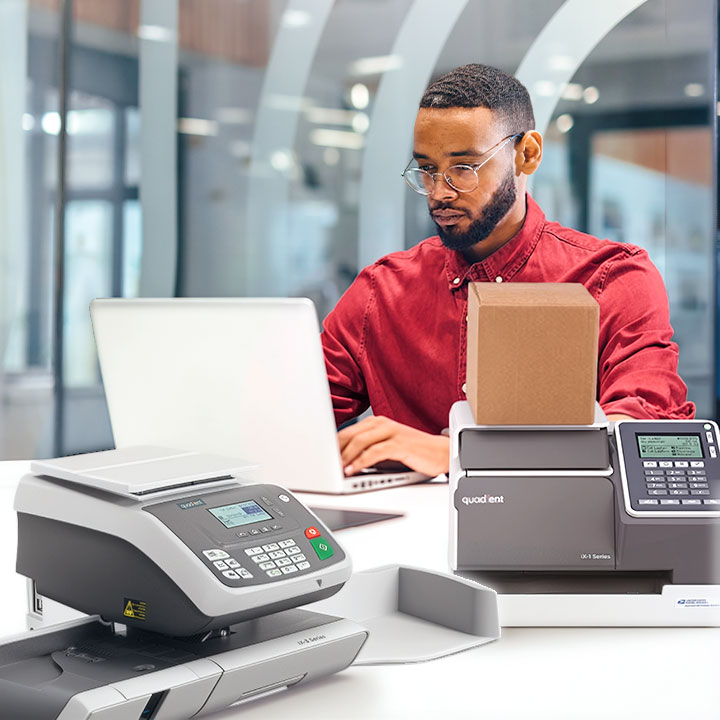 Mat at computer with ix-3 and ix-1 postage meters in the foreground