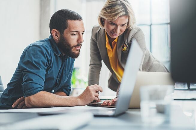 two people looking at a laptop