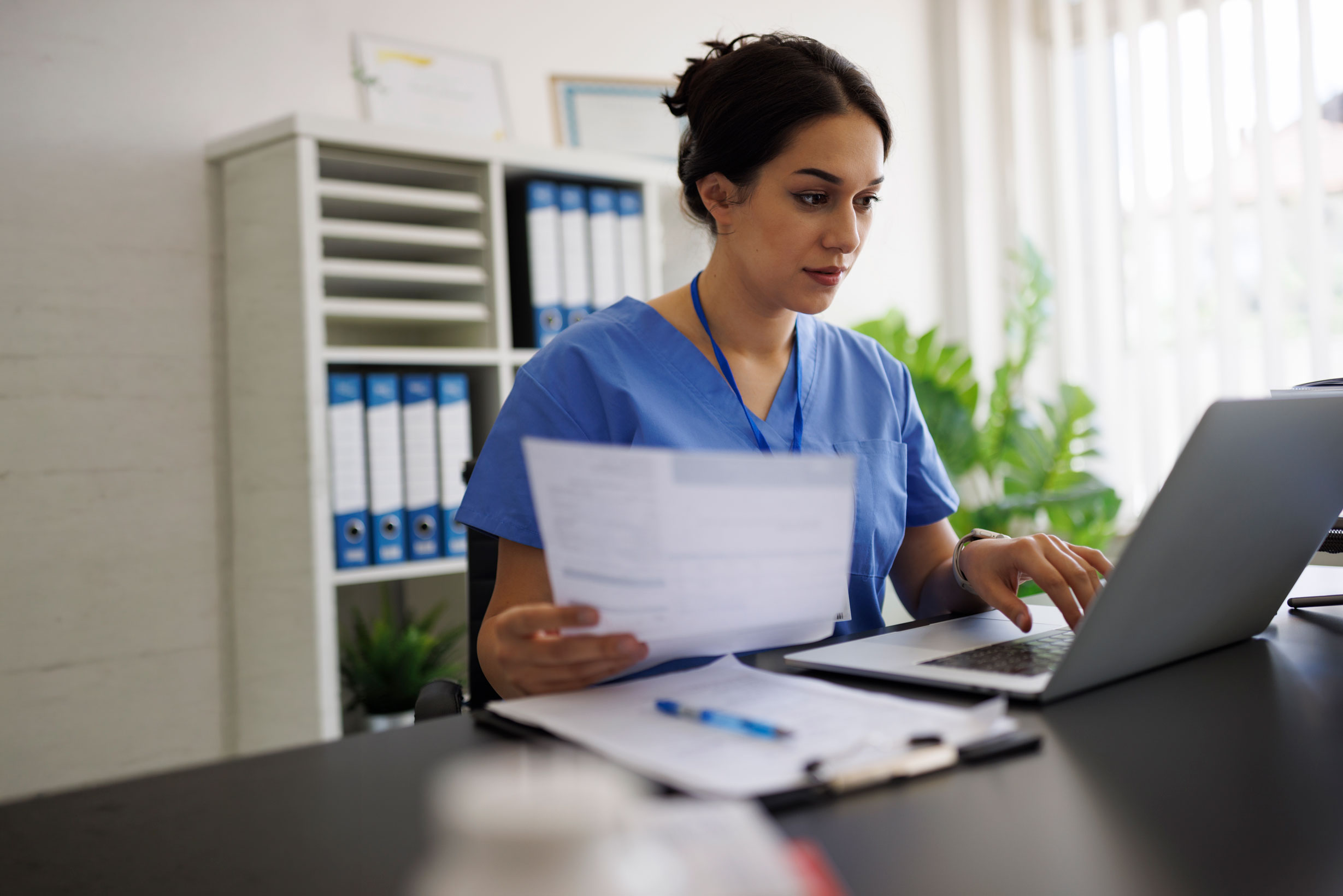 healthcare worker using a computer with an icon that represents contracts and security for documents