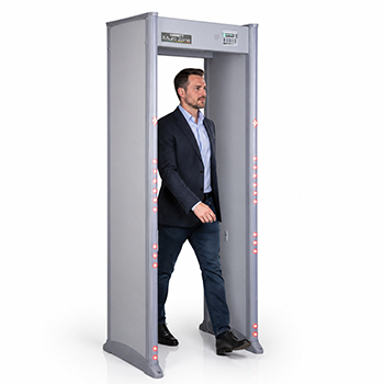 Man in business attire walking through a grey metal detector security gate on white background