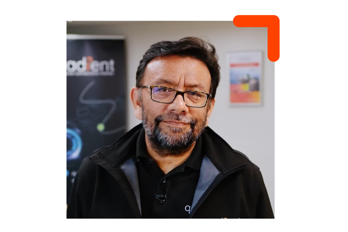 Toujours un homme aux cheveux foncés, à la barbe et à la moustache, portant des lunettes, regardant la caméra