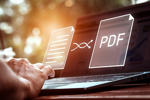 Person using a laptop with floating digital document icons and a highlighted PDF symbol, representing accessible PDF documents and digital document management.