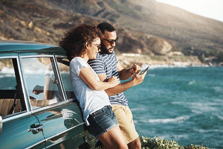 Couple using mobile device on the coast