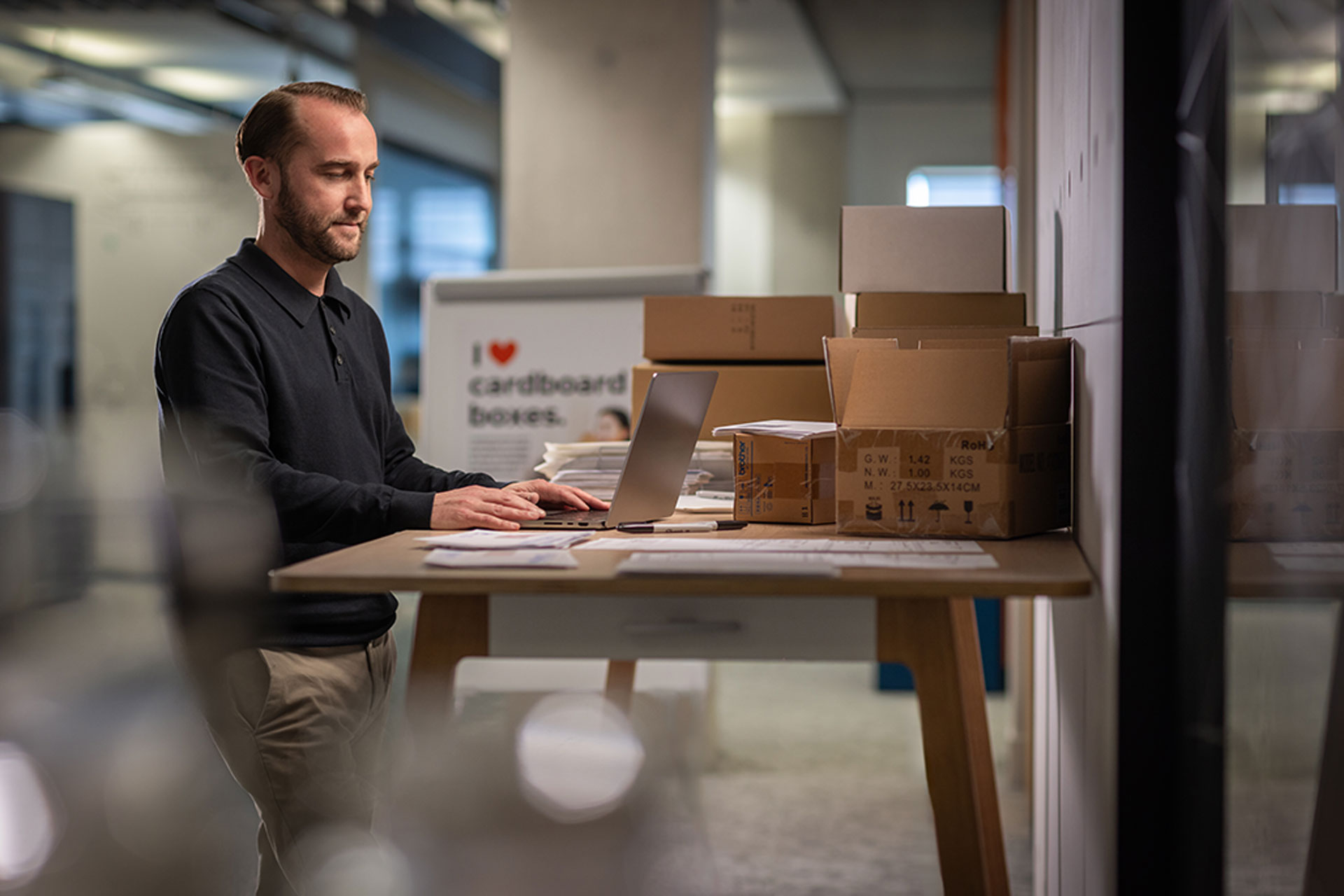 man working at computer packing boxes getting ready for shipping
