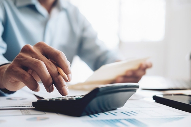 Person using calculator at his desk with financial papers in hand